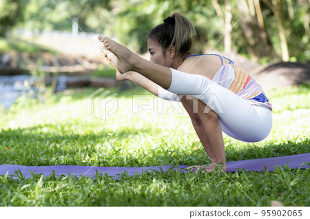 Young woman doing yoga exercises on the outdoor lawn. Young woman doing yoga exercises on the outdoor lawn. 95902065