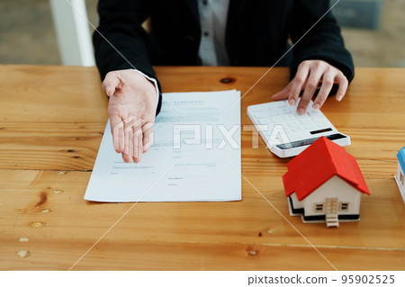 Guarantee, mortgage, contract, contract, signed, real estate agent or bank officer holding a calculator, submits a bid with a customer to buy a home before signing to make a deal. 95902525