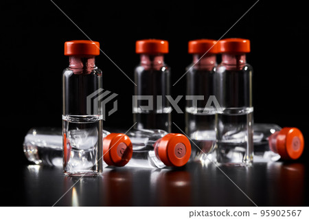 Close-up of medicine for injection in glass vials on a dark background Close-up of medicine for injection in glass vials on a dark background 95902567