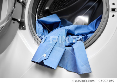 Close-up of an open door in washing machine with dirty shirts inside Close-up of an open door in washing machine with dirty shirts inside 95902569