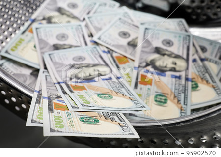 Close-up of washing dollars in machine, money laundering, financial fraud concept Close-up of washing dollars in machine, money laundering, financial fraud concept 95902570
