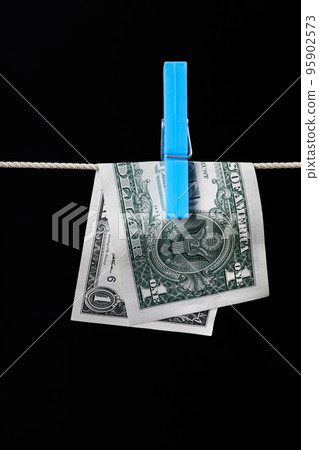 One dollar fastened with a clothespin is dried on a clothesline on a dark background One dollar fastened with a clothespin is dried on a clothesline on a dark background 95902573