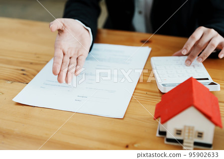 Guarantee, mortgage, contract, contract, signed, real estate agent or bank officer holding a calculator, submits a bid with a customer to buy a home before signing to make a deal. Guarantee, mortgage, contract, contract, signed, real estate agent or bank officer holding a calculator, submits a bid with a customer to buy a home before signing to make a deal. 95902633