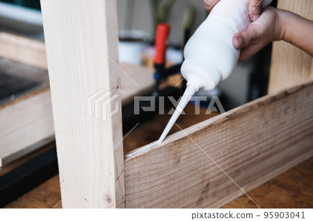 Woodworking operators are using glue to put together the wood parts to assemble and build a wooden table for their customers Woodworking operators are using glue to put together the wood parts to assemble and build a wooden table for their customers 95903041