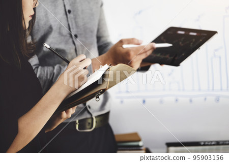 Woman using pen for note with An investment expert points a pen at a tablet monitor to analyze the stock market to teach you how to make a profit Woman using pen for note with An investment expert points a pen at a tablet monitor to analyze the stock market to teach you how to make a profit 95903156