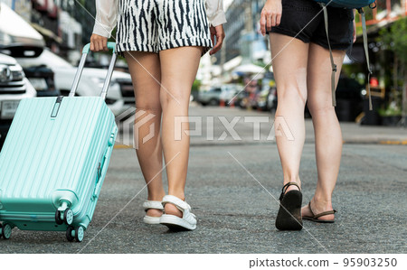 Two travelers with backpacks and bags, taken from behind. 95903250