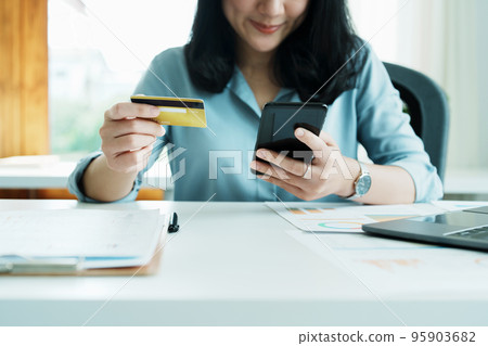 Portrait of young Asian woman using credit card and phone for online shopping. Portrait of young Asian woman using credit card and phone for online shopping. 95903682