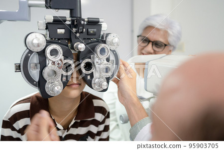 Boy has his eyes checked for glasses by a specialist. Boy has his eyes checked for glasses by a specialist. 95903705