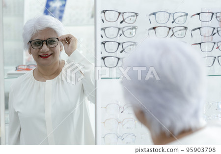 Elderly woman trying on new glasses. Elderly woman trying on new glasses. 95903708