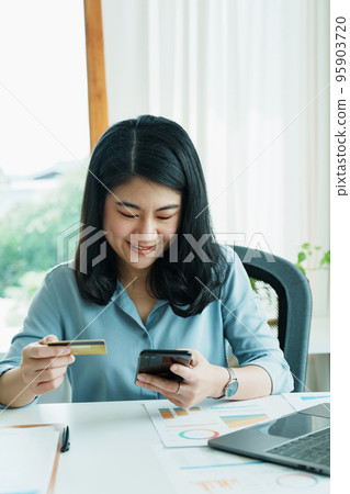 Portrait of young Asian woman using credit card and phone for online shopping. 95903720