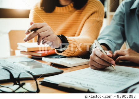 focus consultant holding a pen and the business owner holding a pen reading the terms of a joint venture contract with a partner company 95903898