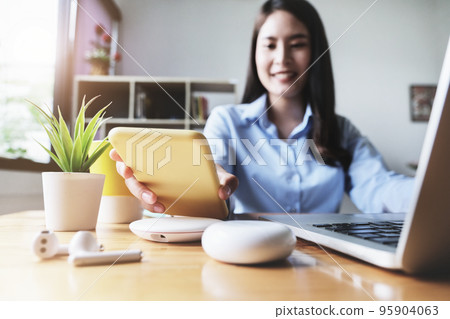 focus Female hand holding Smartphone to Charging at Wireless fast Charging pad at work. vintage tone focus Female hand holding Smartphone to Charging at Wireless fast Charging pad at work. vintage tone 95904063