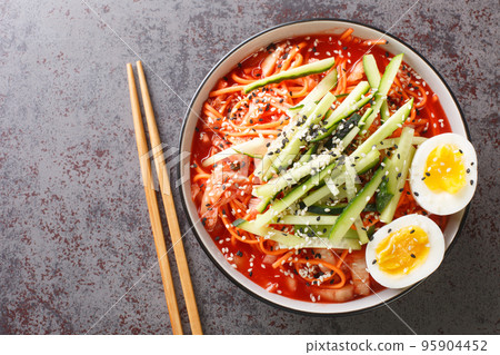 Korean spicy cold noodles Bibim Guksu closeup in the bowl. Horizontal top view Korean spicy cold noodles Bibim Guksu closeup in the bowl. Horizontal top view 95904452