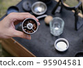 The barista slowbar holds a hand-cranked grinder with coffee beans inside. 95904581
