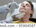 A white man gets a laser facial by a specialist. 95904587