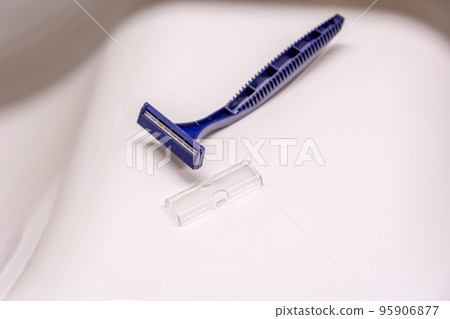 A disposable plastic razor lying on the sink 95906877