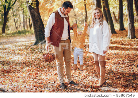 Family have fun in a autumn park. Cute blode in a white sweater. Parents with little son 95907549