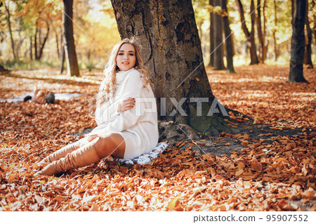 Beautiful girl in a autumn park. Cute blode in a white sweater. Beautiful girl in a autumn park. Cute blode in a white sweater. 95907552