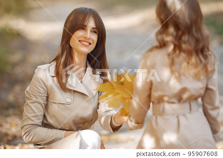 Fashionable mother with daughter. Family in a autumn park. Family with a dog. 95907608
