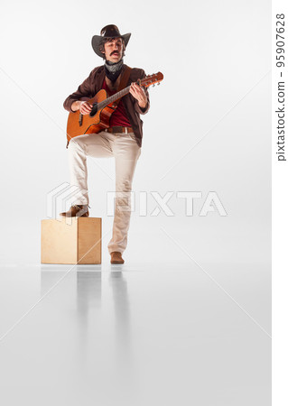 Full-length portrait of man with moustaches in country style clothes playing guitar isolated over white background Full-length portrait of man with moustaches in country style clothes playing guitar isolated over white background 95907628