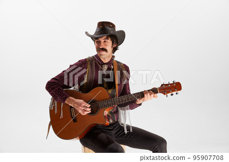 Portrait of man with moustaches in country style clothes playing guitar isolated over white background. Expression of the soul 95907708