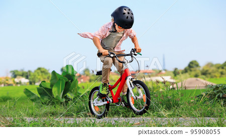 Young rider kid in helmet and sunglasses riding bicycle Young rider kid in helmet and sunglasses riding bicycle 95908055