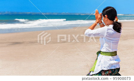 Young balinese women praying with namaste hands on sea beach Young balinese women praying with namaste hands on sea beach 95908073