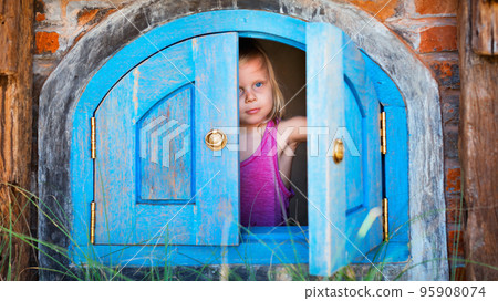 Happy child peek out of toy house window 95908074