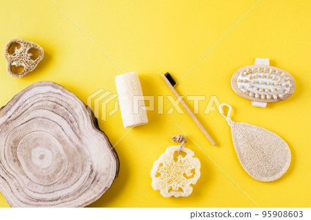 Frame from loofah sponges, massager, toothbrush, wooden comb, wood slice on yellow surface. Collection for bath from ecological material. Zero waste for bath. Copy space, flat lay. Frame from loofah sponges, massager, toothbrush, wooden comb, wood slice on yellow surface. Collection for bath from ecological material. Zero waste for bath. Copy space, flat lay. 95908603