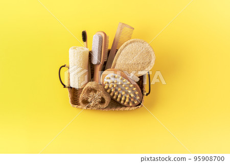 Anti cellulite massager, bamboo toothbrush, loofah sponge, wooden comb, peeling brush in basket on yellow. Eco friendly bathroom accessories. Zero waste concept. Minimalistic style. Anti cellulite massager, bamboo toothbrush, loofah sponge, wooden comb, peeling brush in basket on yellow. Eco friendly bathroom accessories. Zero waste concept. Minimalistic style. 95908700