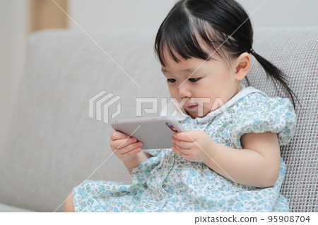 1 year old girl playing with smartphone 95908704