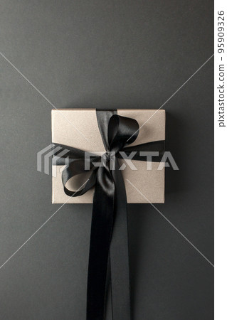 Craft gift box on a dark background, decorated with a textured bow, creating a romantic luxury atmosphere. For birthday, anniversary presents, gift post cards, banner, flyer, invitation, voucher 95909326
