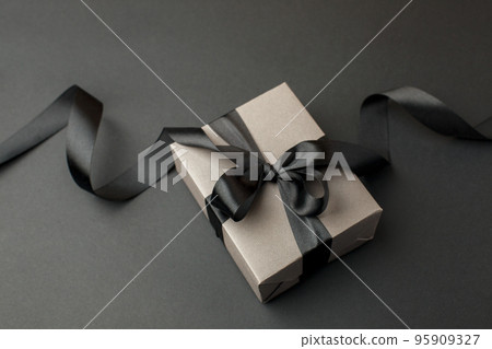 Craft gift box on a dark background, decorated with a textured bow, creating a romantic luxury atmosphere. For birthday, anniversary presents, gift post cards, banner, flyer, invitation, voucher 95909327