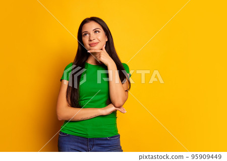 Happy woman with dreams smiling isolated on trendy yellow studio background. Beautiful female half-length portrait. Emotional woman. Human emotions, facial expression concept 95909449