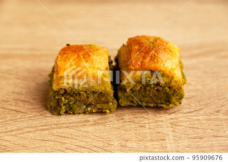 Baklava with pistachio, one of the most beautiful desserts of Turkish cuisine, on oak cutting board 95909676