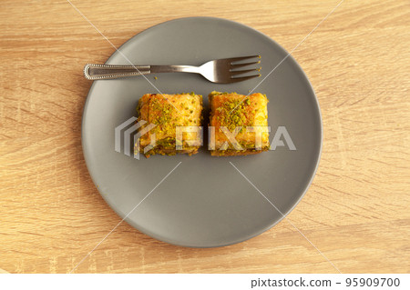 Baklava with pistachio, one of the most beautiful desserts of Turkish cuisine, in gray plate, on oak cutting board 95909700