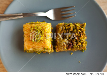 Baklava with pistachio, one of the most beautiful desserts of Turkish cuisine, in gray plate, on oak cutting board 95909701