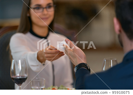 Businessman giving his visit card to woman while having dinner in luxury hotel restaurant 95910075
