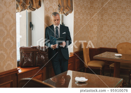 Busy businessman looking at diary while waiting for check in at luxury hotel 95910076