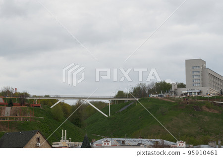 Pedestrian bridge (footbridge) between two green hills in the city center 95910461