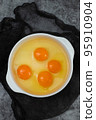 few yellow egg yolks in a white bowl 95910904