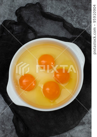few yellow egg yolks in a white bowl 95910904