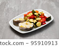 baked vegetables with boiled fish on white plate 95910913