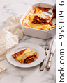 Fresh lasagna with meat and tomato sauce baked in the oven in a ceramic dish. 95910916
