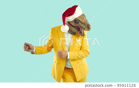 Happy man in a yellow suit, dinosaur mask and Christmas hat dancing on a turquoise background 95911128