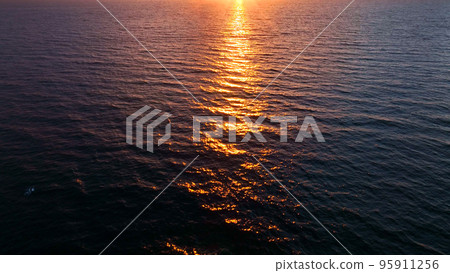 Sunset aerial shot above ocean surface in sunrise golden hour, close-up 95911256