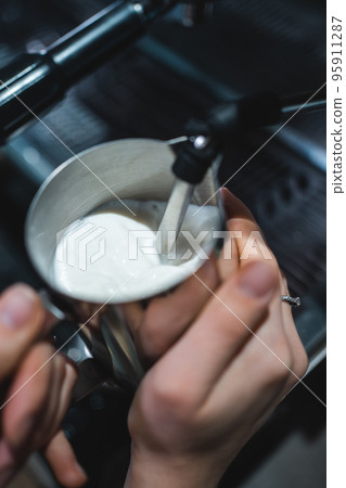 barista heating fresh milk for making cappuccino or latte coffee hot drink barista heating fresh milk for making cappuccino or latte coffee hot drink 95911287