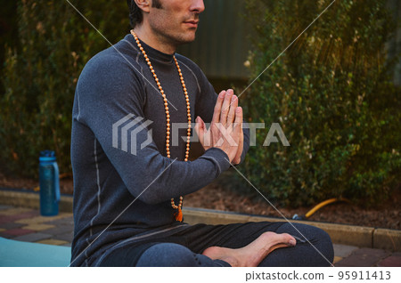 A man athlete, yogi in gray sportswear, sitting folded palms together, practicing yoga. Hands folded in prayer. Hands together. Prayer, gratitude. Yoga hand pose. Folded hands. Palm pressed. A man athlete, yogi in gray sportswear, sitting folded palms together, practicing yoga. Hands folded in prayer. Hands together. Prayer, gratitude. Yoga hand pose. Folded hands. Palm pressed. 95911413