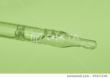 Pipette with liquid essence on a light green background. Serum for the face. The concept of an extract for cosmetic purposes. High quality photo 95911549