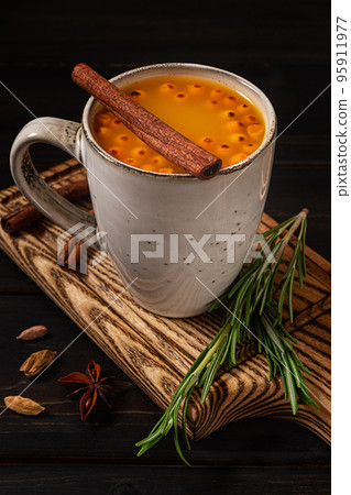 A cup of sea buckthorn hot drink on dark wooden background 95911977